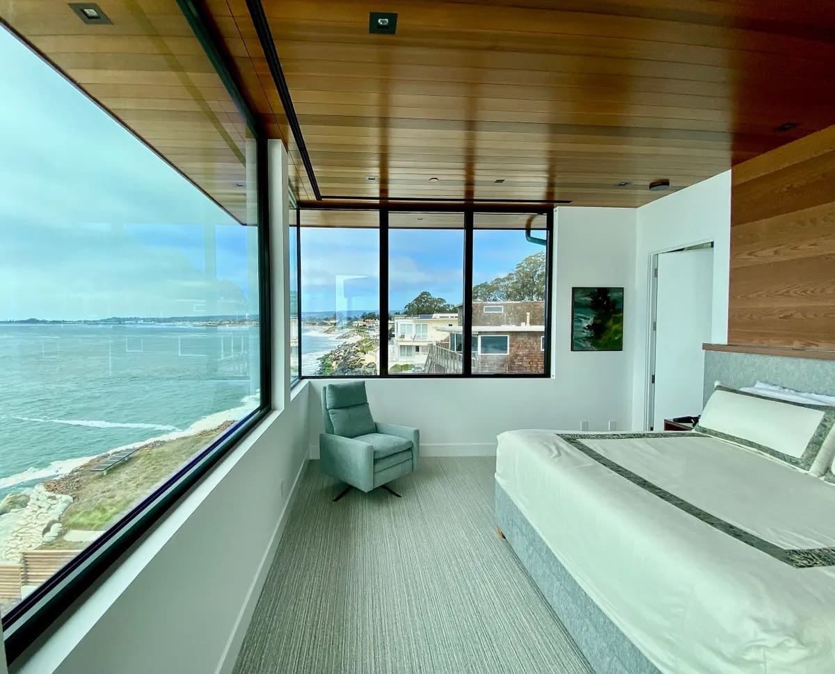 A bedroom with a large window overlooking the ocean.