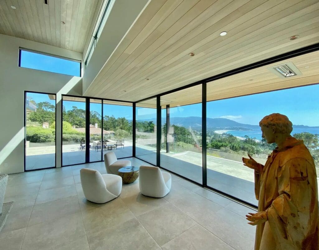 A woman standing in front of large windows.