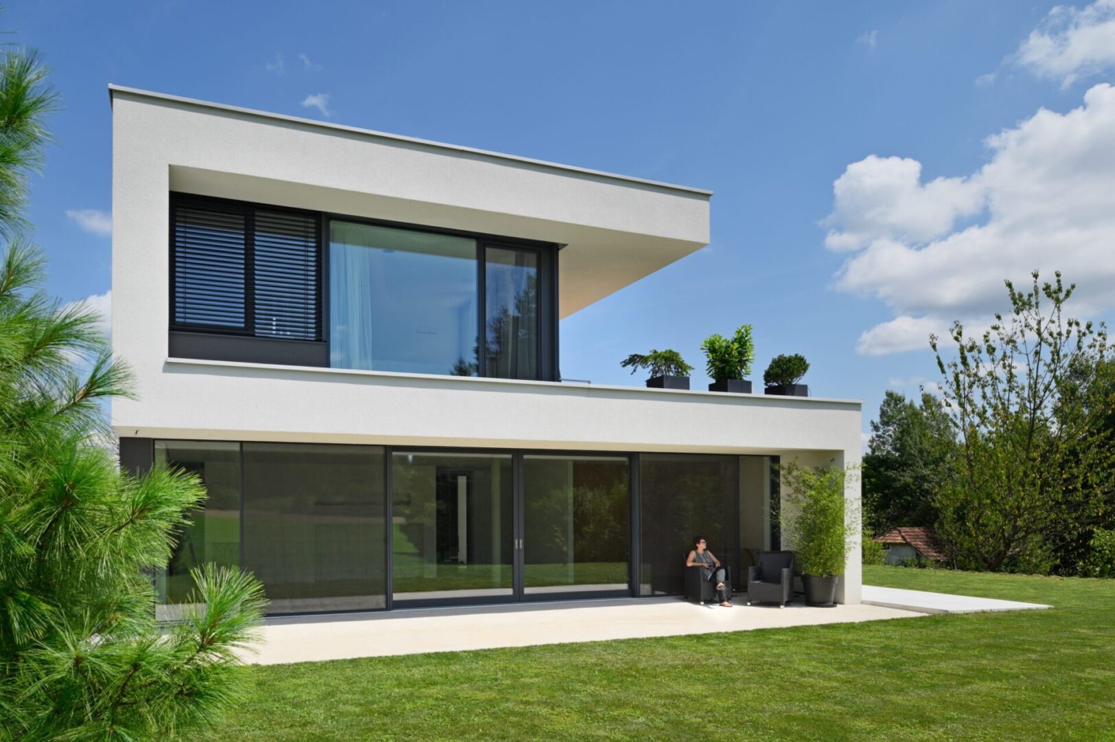 A person sitting on the grass outside of a house.